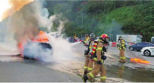 지난 29일 오전 8시 10분께 경기 의왕시 서울외곽순환고속도로 판교 방향 청계 톨게이트 부근을 주행하던 BMW 차량에서 불이 나 소방대원들이 진화 작업을 벌이고 있다.  연합뉴스